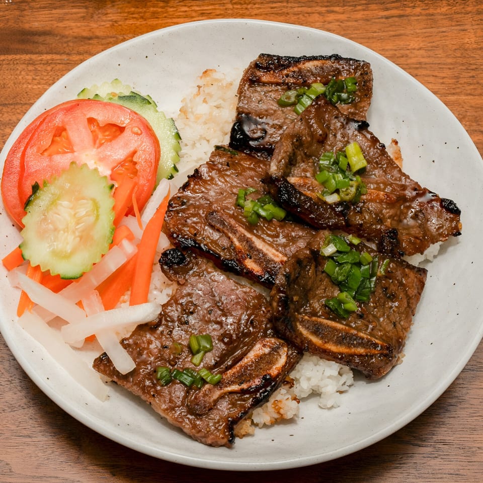 Grilled short ribs with green onions, served over rice with sliced tomatoes, cucumbers, and pickled vegetables.