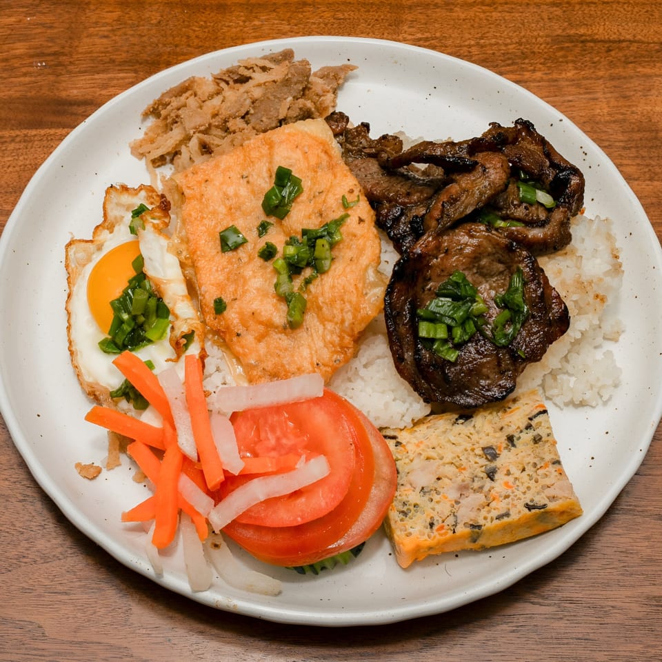 Ooh Pho's Vietnamese broken rice dish with grilled pork, fried egg, pork chop, and vegetables.