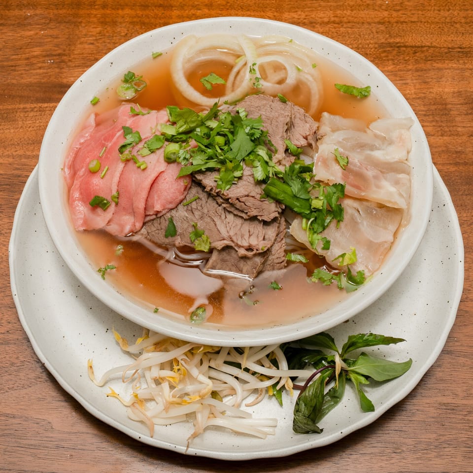 Ooh Pho's Vietnamese pho with various cuts of beef, onions, and herbs, served with bean sprouts.