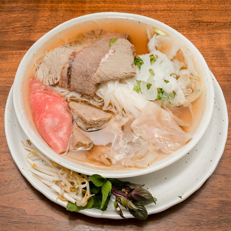 Ooh Pho's Vietnamese pho with various cuts of beef, noodles, and broth, garnished with fresh herbs.